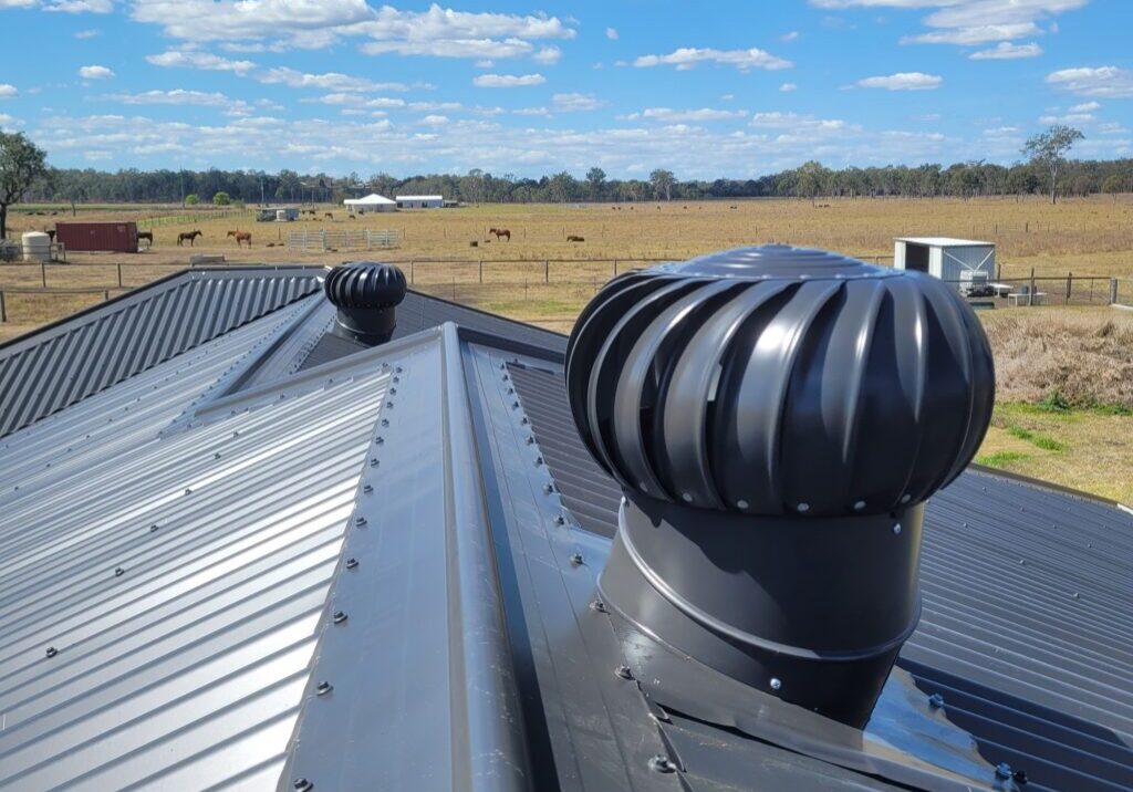 Two whirlybirds installed on a grey metal roof